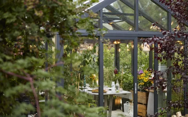 Une véranda dans un style verrière végétalisée, avec salon de jardin