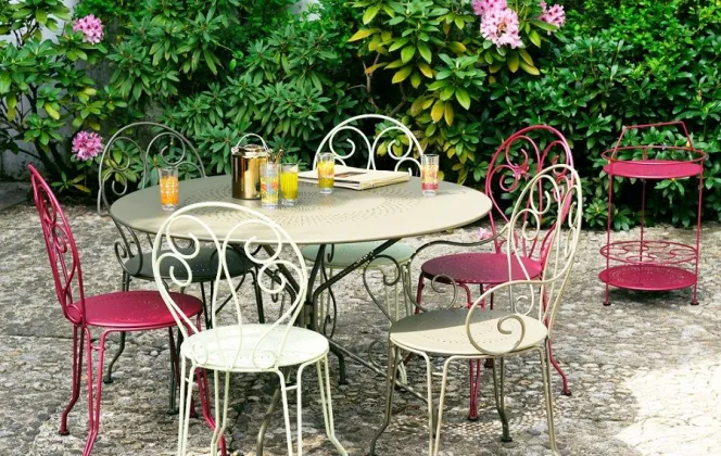 Ce petit salon de jardin comportant une table et six chaises en fil acier allie tradition et confort. © Fermob